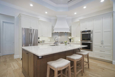 Mid-sized trendy u-shaped light wood floor and beige floor eat-in kitchen photo in Miami with an undermount sink, shaker cabinets, white cabinets, quartzite countertops, gray backsplash, subway tile backsplash, stainless steel appliances and an island