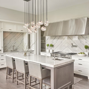 Inspiration for a transitional l-shaped dark wood floor and gray floor kitchen remodel in Chicago with a single-bowl sink, white cabinets, quartzite countertops, stainless steel appliances, shaker cabinets, white backsplash, an island, stone slab backsplash and gray countertops