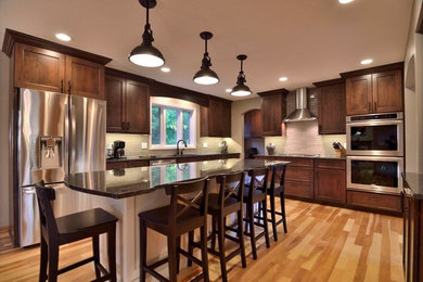 Diseño de cocina clásica con fregadero bajoencimera, puertas de armario de madera en tonos medios, salpicadero blanco y electrodomésticos de acero inoxidable