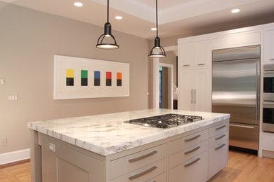 Mid-sized trendy l-shaped light wood floor eat-in kitchen photo in New York with a single-bowl sink, recessed-panel cabinets, white cabinets, marble countertops, beige backsplash, glass sheet backsplash, stainless steel appliances and an island