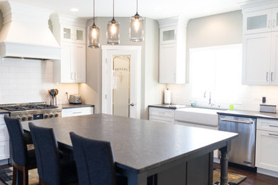 Example of a large transitional u-shaped eat-in kitchen design in Other with a farmhouse sink, flat-panel cabinets, white cabinets, granite countertops, white backsplash, ceramic backsplash, stainless steel appliances and an island