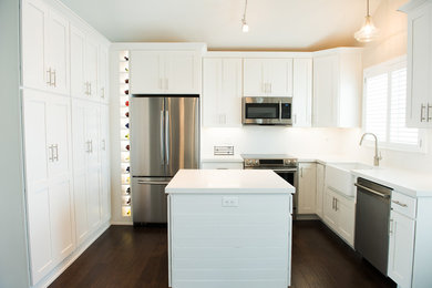 Small transitional u-shaped dark wood floor and brown floor eat-in kitchen photo in Other with a farmhouse sink, shaker cabinets, white cabinets, quartz countertops, white backsplash, subway tile backsplash, stainless steel appliances and an island