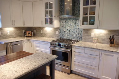 Example of a mid-sized transitional l-shaped porcelain tile and beige floor eat-in kitchen design in Other with shaker cabinets, white cabinets, wood countertops, gray backsplash, stainless steel appliances, an island, a farmhouse sink and subway tile backsplash