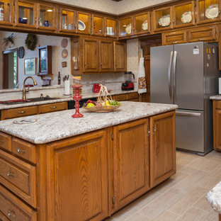 Mid-sized traditional u-shaped separate kitchen in Dallas with raised-panel cabinets, medium wood cabinets, quartz benchtops, beige splashback, ceramic splashback, stainless steel appliances, laminate floors, with island, beige floor and a double-bowl sink.