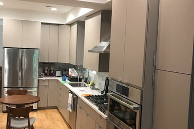 シカゴにある高級なモダンスタイルのおしゃれなキッチン (シングルシンク、フラットパネル扉のキャビネット、グレーのキャビネット、珪岩カウンター、白いキッチンパネル、ガラスタイルのキッチンパネル、シルバーの調理設備、淡色無垢フローリング) の写真