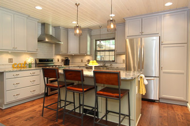 Large eclectic l-shaped medium tone wood floor eat-in kitchen photo in Grand Rapids with a farmhouse sink, recessed-panel cabinets, gray cabinets, granite countertops, white backsplash, subway tile backsplash, stainless steel appliances and an island