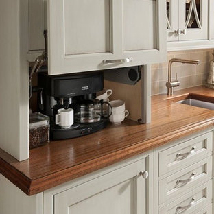 Small traditional single-wall eat-in kitchen in Houston with an undermount sink, recessed-panel cabinets, grey cabinets, wood benchtops, grey splashback, glass tile splashback, black appliances and vinyl floors.