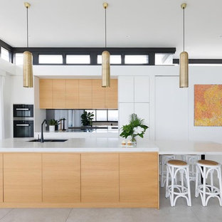 This is an example of a contemporary galley eat-in kitchen in Sydney with black appliances, ceramic floors, grey floor, an undermount sink, flat-panel cabinets, medium wood cabinets, mirror splashback, with island, marble benchtops and multi-coloured benchtop.