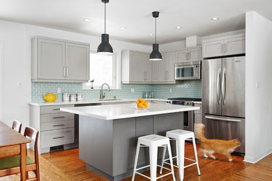 Eat-in kitchen - transitional l-shaped medium tone wood floor eat-in kitchen idea in Toronto with an undermount sink, shaker cabinets, gray cabinets, subway tile backsplash, stainless steel appliances, an island, white countertops and blue backsplash