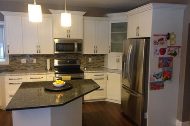 Example of a transitional kitchen design in Toronto with white cabinets, granite countertops and an island