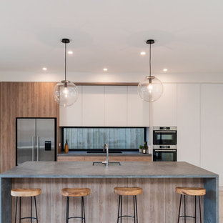 Inspiration for a contemporary galley kitchen in Melbourne with an undermount sink, flat-panel cabinets, medium wood cabinets, window splashback, stainless steel appliances, bamboo floors, with island, beige floor and grey benchtop.