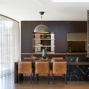 Inspiration for a contemporary galley kitchen in Sydney with flat-panel cabinets, dark wood cabinets, mirror splashback, with island, brown floor and black benchtop.
