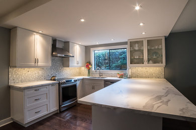 Modern inredning av ett mellanstort u-kök, med en undermonterad diskho, skåp i shakerstil, vita skåp, bänkskiva i betong, gult stänkskydd, stänkskydd i stenkakel, rostfria vitvaror, mellanmörkt trägolv och en halv köksö