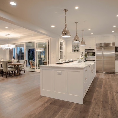 Open concept kitchen - huge farmhouse l-shaped dark wood floor open concept kitchen idea in Seattle with a farmhouse sink, shaker cabinets, white cabinets, marble countertops, white backsplash, stone tile backsplash, stainless steel appliances and an island
