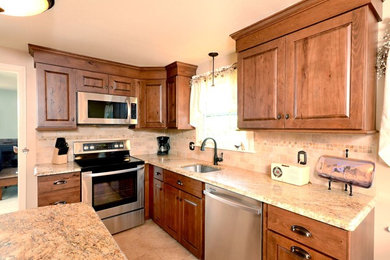 Example of a mid-sized classic l-shaped ceramic tile eat-in kitchen design in Bridgeport with an undermount sink, raised-panel cabinets, medium tone wood cabinets, granite countertops, beige backsplash, ceramic backsplash, stainless steel appliances and an island