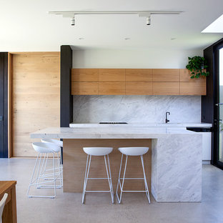 Photo of a mid-sized contemporary eat-in kitchen in Melbourne with with island, flat-panel cabinets, medium wood cabinets, white splashback, concrete floors, grey floor and white benchtop.
