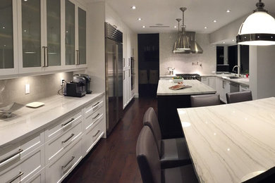 Example of a mid-sized trendy u-shaped dark wood floor enclosed kitchen design in Miami with an undermount sink, shaker cabinets, white cabinets, marble countertops, gray backsplash, stainless steel appliances and two islands