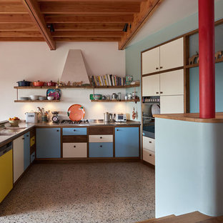 Imagen de cocina en U, retro, de tamaño medio, abierta, con fregadero de doble seno, armarios con paneles lisos, encimera de acero inoxidable, electrodomésticos de acero inoxidable, suelo de madera oscura y suelo marrón