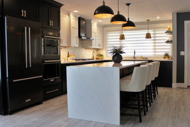 Example of a large transitional l-shaped vinyl floor and gray floor open concept kitchen design in Other with an undermount sink, flat-panel cabinets, black cabinets, quartz countertops, white backsplash, marble backsplash, black appliances and an island