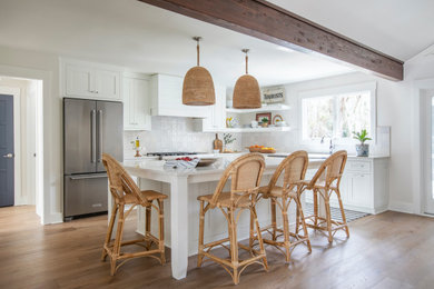 Beach style u-shaped medium tone wood floor, brown floor and exposed beam open concept kitchen photo in Jacksonville with an undermount sink, shaker cabinets, white cabinets, marble countertops, white backsplash, stainless steel appliances, an island and gray countertops