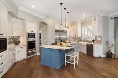 Inspiration for a large coastal medium tone wood floor open concept kitchen remodel in Orange County with a farmhouse sink, white cabinets, quartz countertops, multicolored backsplash, glass tile backsplash, stainless steel appliances and an island