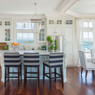 Mid-sized beach style medium tone wood floor eat-in kitchen photo in Providence with recessed-panel cabinets, white cabinets, marble countertops, white backsplash, ceramic backsplash, stainless steel appliances and an island