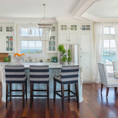 Mid-sized beach style medium tone wood floor eat-in kitchen photo in Providence with recessed-panel cabinets, white cabinets, marble countertops, white backsplash, ceramic backsplash, stainless steel appliances and an island