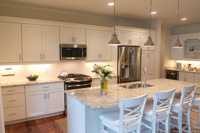 Example of a large beach style galley medium tone wood floor eat-in kitchen design in Providence with a double-bowl sink, shaker cabinets, white cabinets, white backsplash, ceramic backsplash, stainless steel appliances and an island