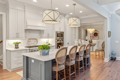 Beach style galley kitchen photo in Other with white cabinets, quartzite countertops, an island and white countertops