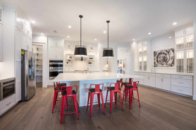 Mid-sized cottage u-shaped medium tone wood floor and brown floor open concept kitchen photo in Jacksonville with a farmhouse sink, shaker cabinets, white cabinets, quartz countertops, white backsplash, subway tile backsplash, stainless steel appliances, an island and white countertops