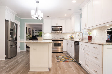 Example of a mid-sized beach style u-shaped vinyl floor and brown floor enclosed kitchen design in Other with an undermount sink, shaker cabinets, white cabinets, stainless steel appliances, an island, marble countertops, gray backsplash and marble backsplash
