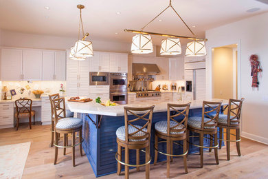 Kitchen - mid-sized coastal l-shaped light wood floor and beige floor kitchen idea in San Diego with louvered cabinets, white cabinets, marble countertops, white backsplash, an island, white countertops, marble backsplash and paneled appliances