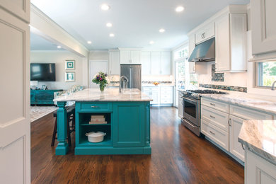 Example of a large beach style u-shaped plywood floor and brown floor open concept kitchen design in New York with an undermount sink, recessed-panel cabinets, white cabinets, marble countertops, white backsplash, subway tile backsplash, stainless steel appliances, an island and white countertops