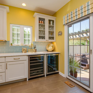 Large beach style l-shaped open plan kitchen in Other with an undermount sink, flat-panel cabinets, white cabinets, quartz benchtops, blue splashback, porcelain splashback, stainless steel appliances, porcelain floors, with island, brown floor and white benchtop.