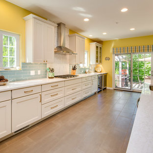 Photo of a large beach style l-shaped open plan kitchen in Other with an undermount sink, flat-panel cabinets, white cabinets, quartz benchtops, blue splashback, porcelain splashback, stainless steel appliances, porcelain floors, with island, brown floor and white benchtop.