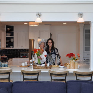 Photo of a large beach style u-shaped eat-in kitchen in Orlando with a farmhouse sink, shaker cabinets, white cabinets, quartz benchtops, blue splashback, ceramic splashback, stainless steel appliances, ceramic floors and a peninsula.