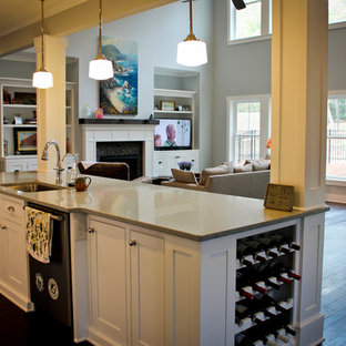 This is an example of a mid-sized beach style galley open plan kitchen in Raleigh with shaker cabinets, white cabinets, with island, an undermount sink, glass tile splashback, white appliances and dark hardwood floors.
