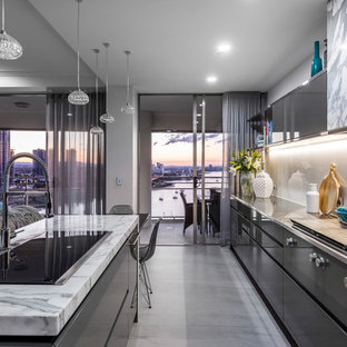 Design ideas for a contemporary galley open plan kitchen in Gold Coast - Tweed with a drop-in sink, flat-panel cabinets, grey cabinets, grey splashback, glass sheet splashback, panelled appliances, concrete floors, with island and grey floor.