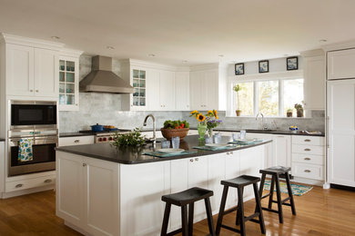 Klassische Küche in L-Form mit Unterbauwaschbecken, Schrankfronten im Shaker-Stil, weißen Schränken, Küchenrückwand in Grau, Küchengeräten aus Edelstahl, hellem Holzboden und Rückwand aus Marmor in Boston