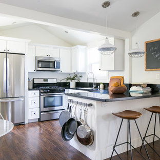 Photo of a small farmhouse u-shaped open plan kitchen in Orange County with a submerged sink, shaker cabinets, white cabinets, granite worktops, black splashback, stone slab splashback, stainless steel appliances and vinyl flooring.