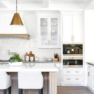 Foto di una grande cucina minimalista con ante bianche, top in superficie solida, paraspruzzi bianco, elettrodomestici in acciaio inossidabile, pavimento in legno massello medio, pavimento grigio e ante a filo