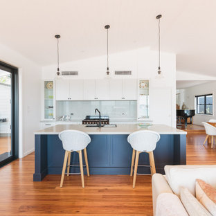 Photo of a large beach style open plan kitchen in Newcastle - Maitland with shaker cabinets, white cabinets, quartz benchtops, grey splashback, with island, white benchtop, an undermount sink, medium hardwood floors and vaulted.