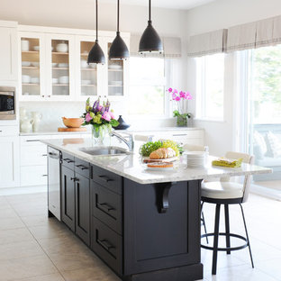 Large traditional l-shaped eat-in kitchen in Vancouver with an undermount sink, shaker cabinets, white cabinets, granite benchtops, white splashback, glass tile splashback, stainless steel appliances, porcelain floors and with island.