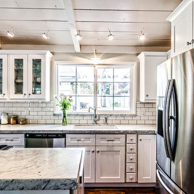 Mid-sized arts and crafts l-shaped dark wood floor and brown floor open concept kitchen photo in San Diego with an undermount sink, shaker cabinets, white cabinets, granite countertops, white backsplash, subway tile backsplash, stainless steel appliances and an island
