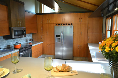 Example of a mid-sized minimalist u-shaped eat-in kitchen design in Philadelphia with flat-panel cabinets, medium tone wood cabinets, solid surface countertops and a peninsula