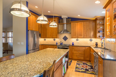 Example of a classic l-shaped light wood floor enclosed kitchen design in Other with an undermount sink, shaker cabinets, medium tone wood cabinets, white backsplash, mosaic tile backsplash, stainless steel appliances, an island and multicolored countertops
