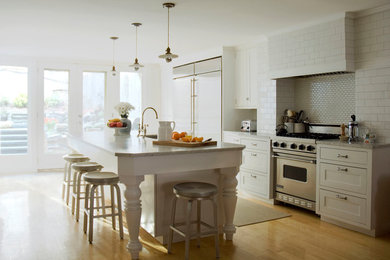 Large classic kitchen/diner in New York with a double-bowl sink, shaker cabinets, white cabinets, marble worktops, white splashback, ceramic splashback, stainless steel appliances, light hardwood flooring, an island, beige floors and grey worktops.