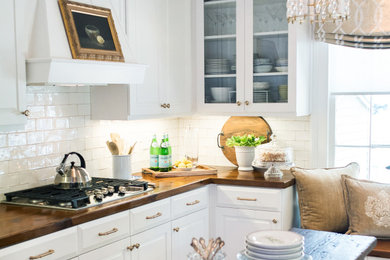Inspiration for a mid-sized farmhouse u-shaped medium tone wood floor and brown floor eat-in kitchen remodel in Charleston with a double-bowl sink, raised-panel cabinets, white cabinets, wood countertops, white backsplash, subway tile backsplash, stainless steel appliances, an island and brown countertops