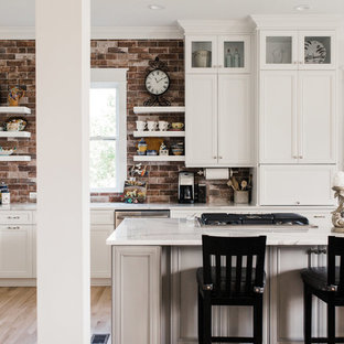 Mid-sized transitional u-shaped eat-in kitchen in Charleston with white cabinets, brick splashback, with island, an undermount sink, shaker cabinets, quartz benchtops, red splashback, stainless steel appliances, light hardwood floors, beige floor and white benchtop.