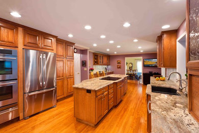 Large elegant galley medium tone wood floor eat-in kitchen photo in Baltimore with an undermount sink, raised-panel cabinets, medium tone wood cabinets, multicolored backsplash, stainless steel appliances, two islands and granite countertops